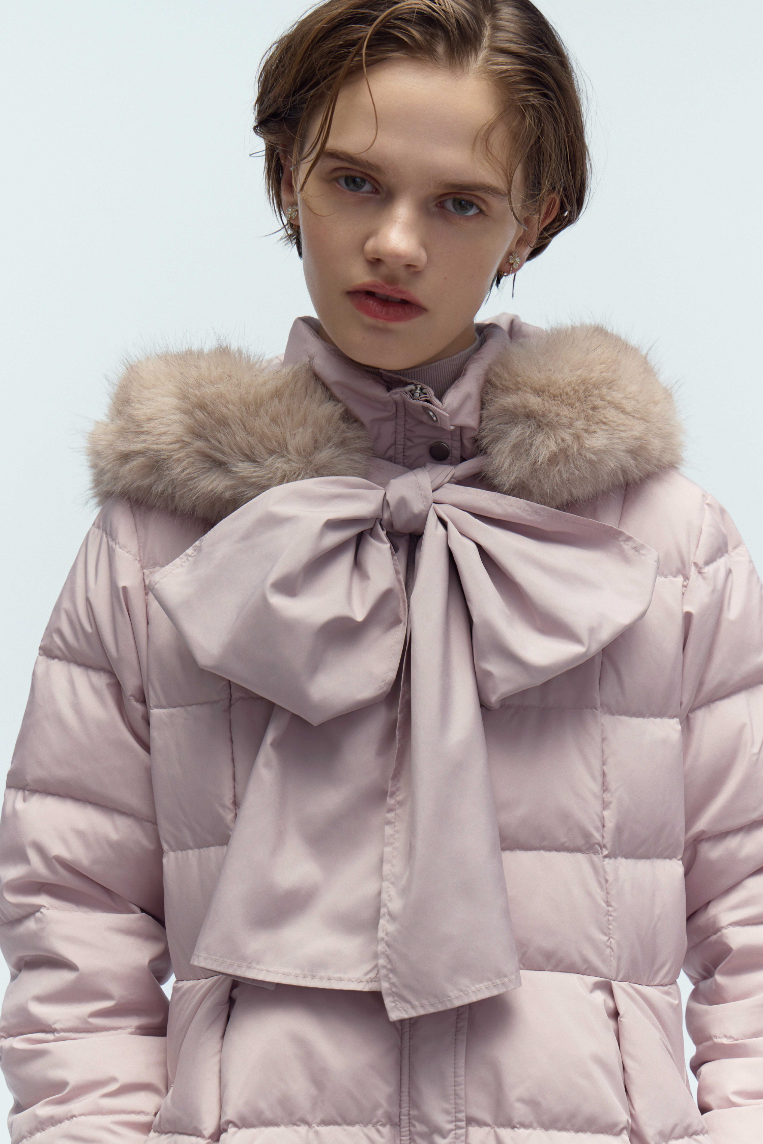 ライトピンク色のフードリボンロングダウンコートを着用したモデル画像