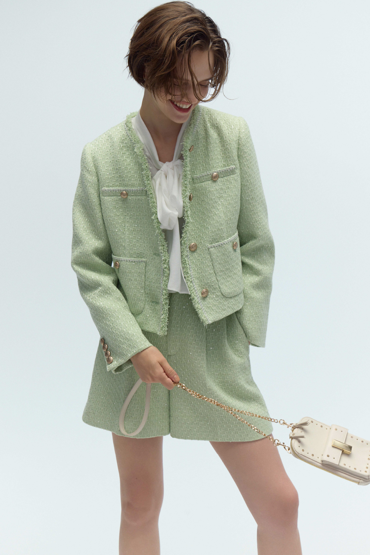 ミント色のフリンジツイードジャケットとバリエーションショートパンツ、アイボリー色のリュタンビジュースタッズマルチショルダー、白色のビッグリボンセミシアーブラウスを着用したモデル画像
