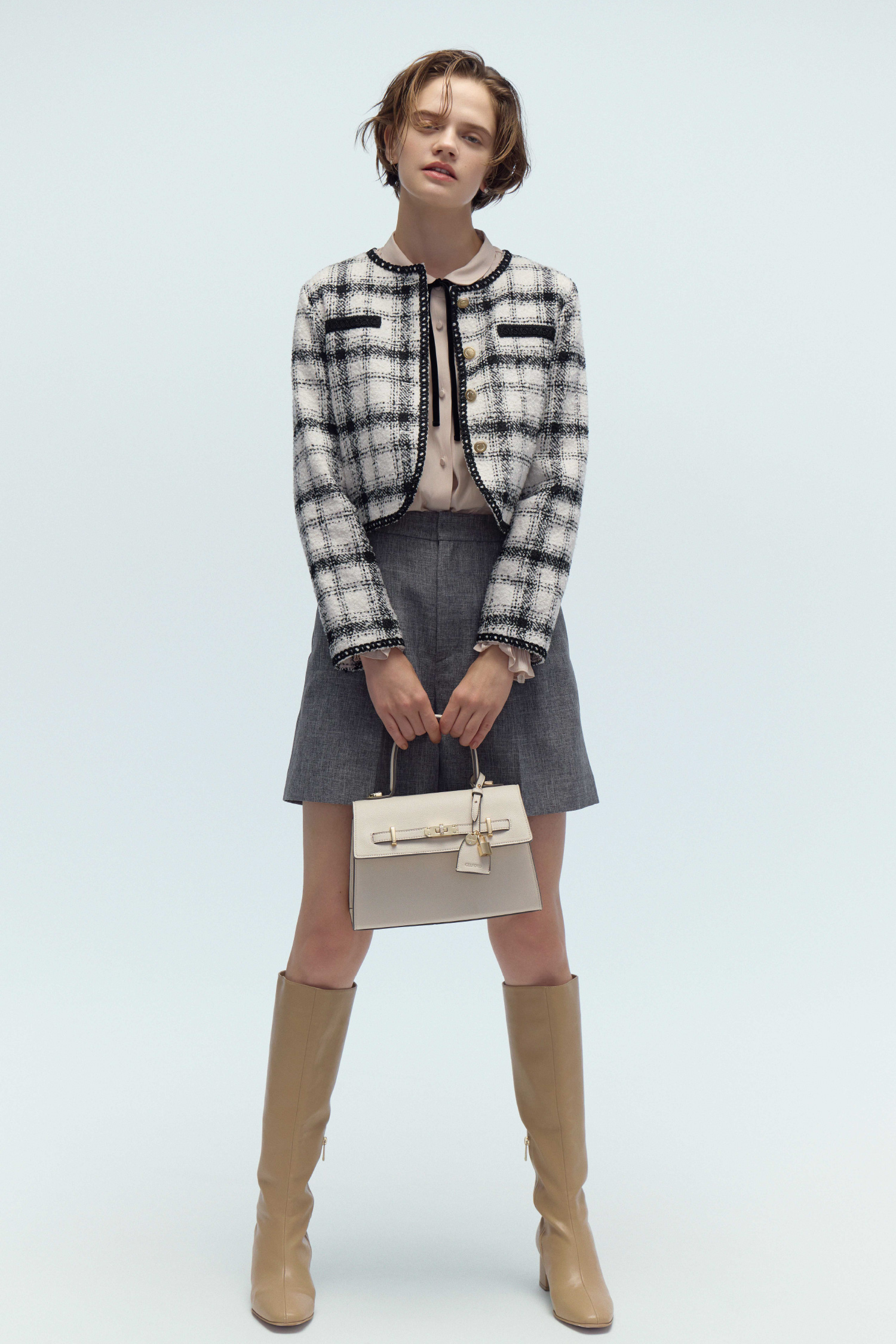 バリエーションライトジャケット、フリルヨークシャツカラーブラウス、バリエーションショートパンツ、パヴェビジューハートピアス、ビジューツイストバックルハンドバッグ、ロゴメタル付きロングブーツの着用イメージ