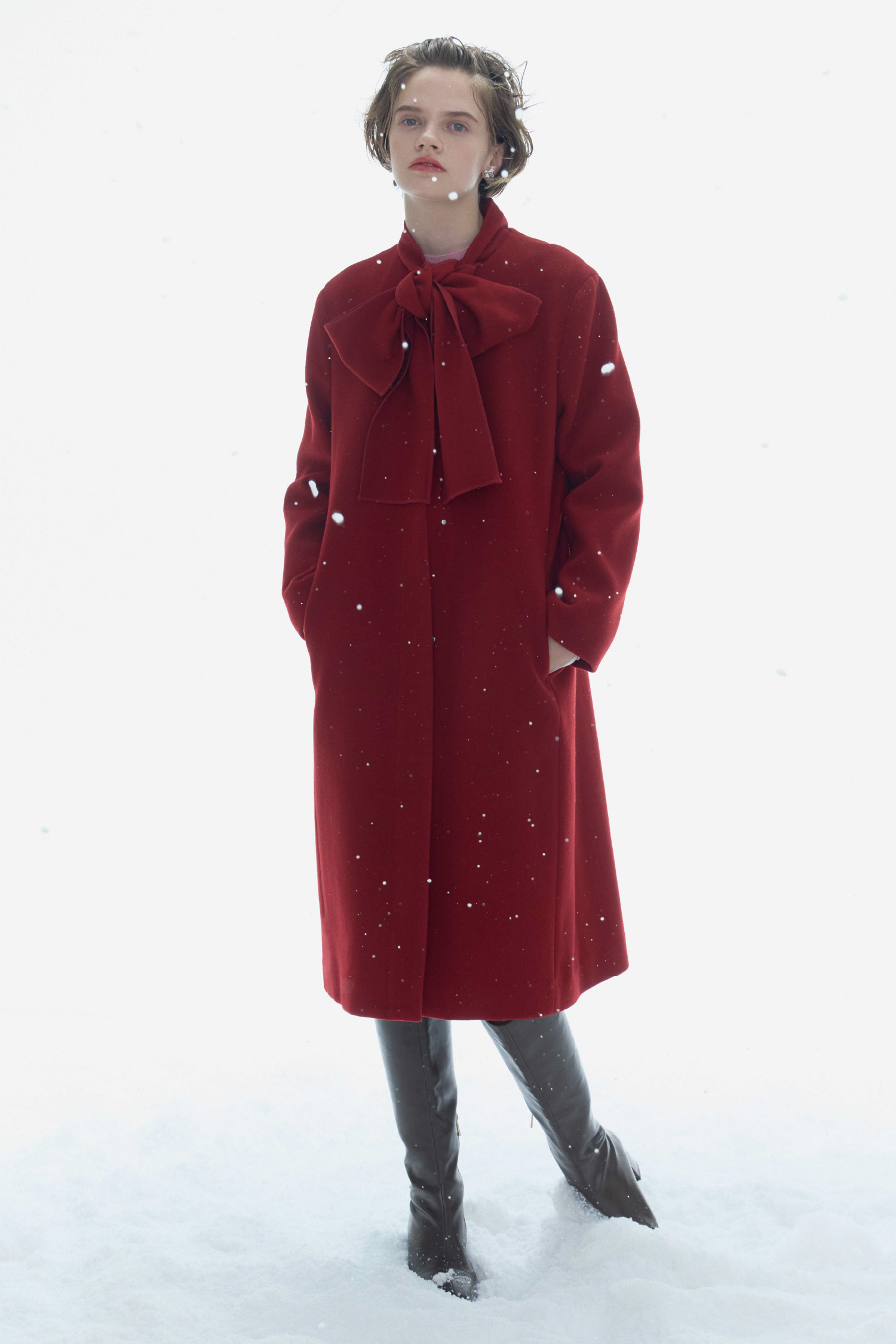 赤色のリボンストール付きノーカラーコートとブラウン色のロゴメタル付きロングブーツを着用したモデル画像