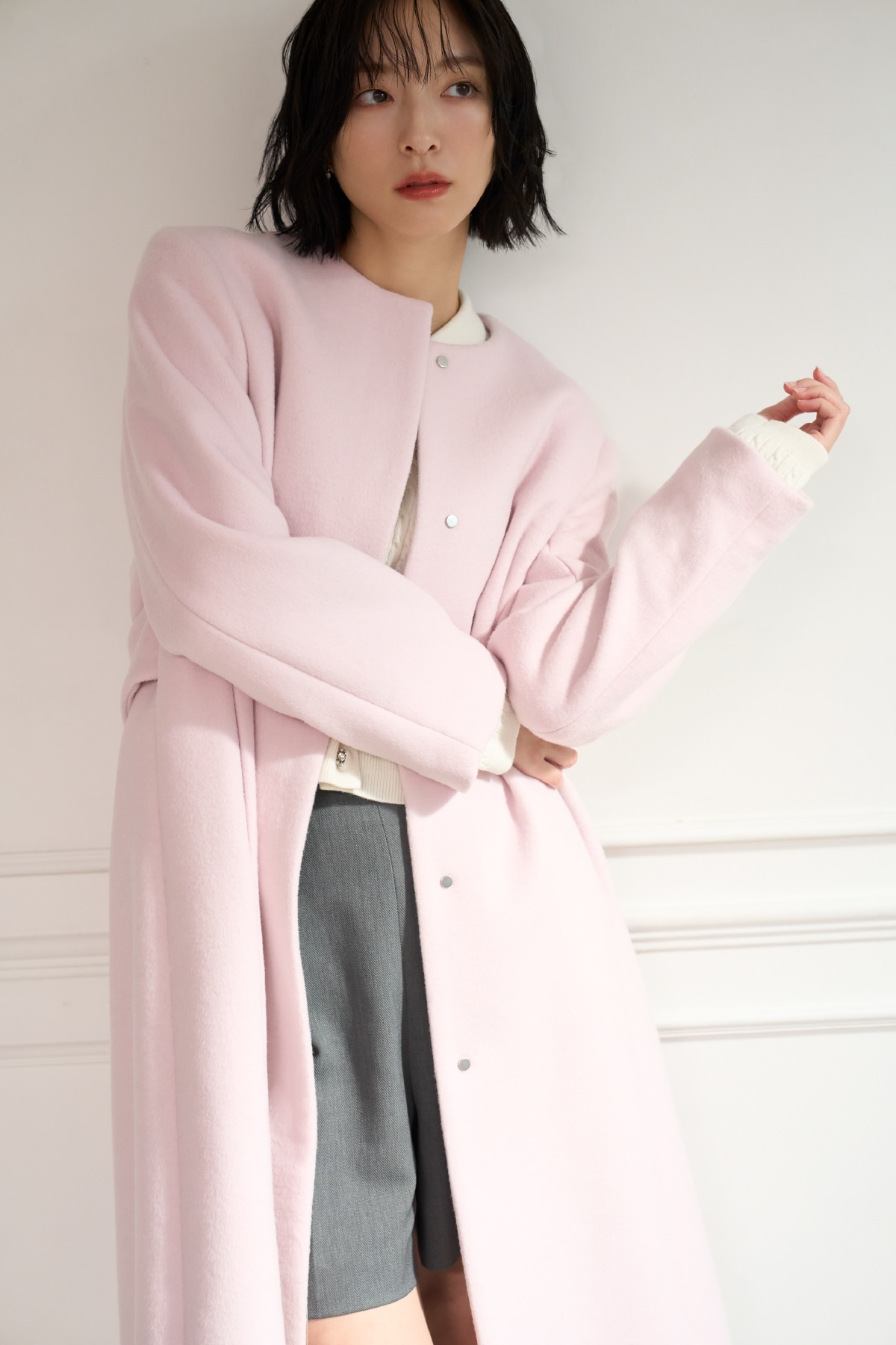 ピンクのロングコートに白のニットトップスとグレーのキュロットを着た女性の前向きの写真