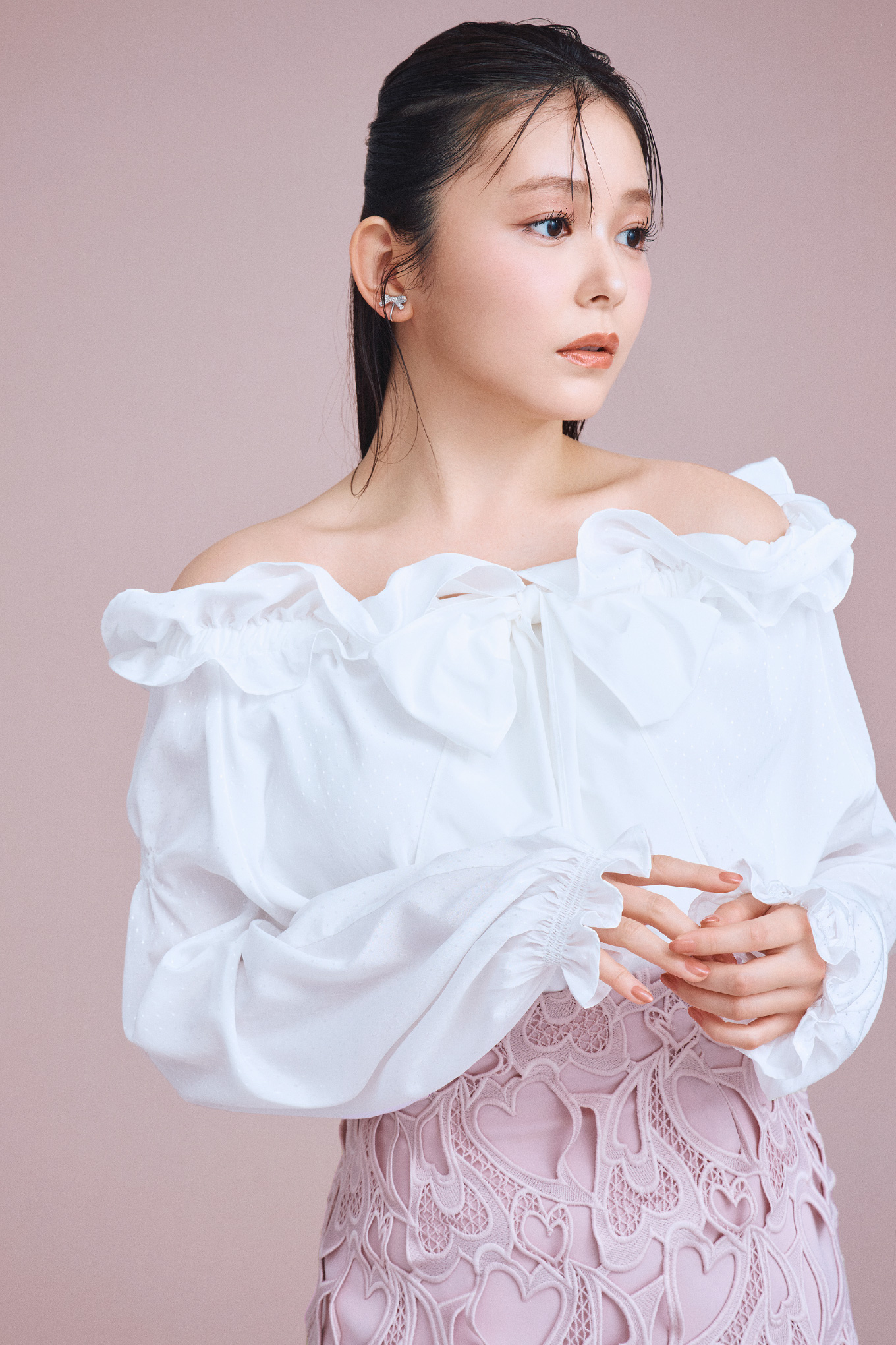 白色のビッグリボンスモックブラウス、ピンク色の【WEB限定サイス】ハートレースタイトスカート、リボンビジューイヤリングを着用した女性のイメージ