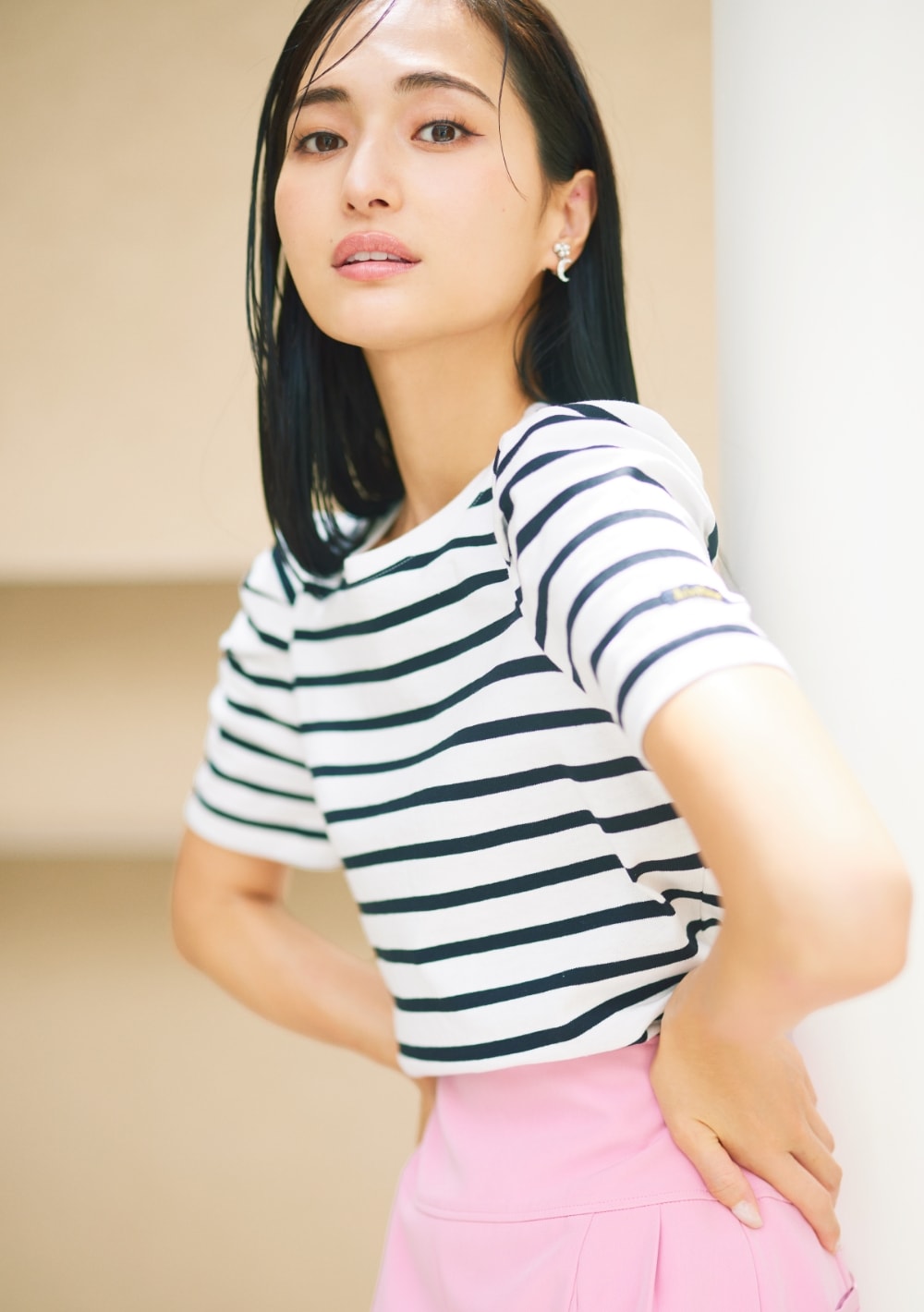 ピンクのパンツにボーダーのトップスを着た女性が腰に手を当てて振り向いている画像