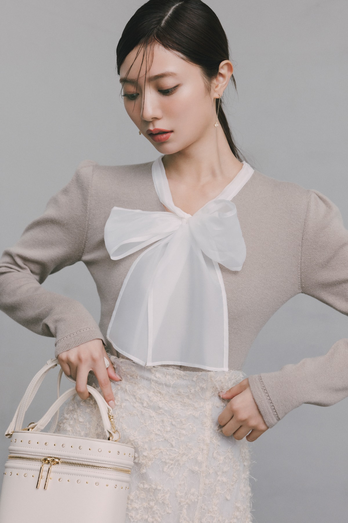 ベージュのトップスにスカートを着た女性が正面を向いている画像