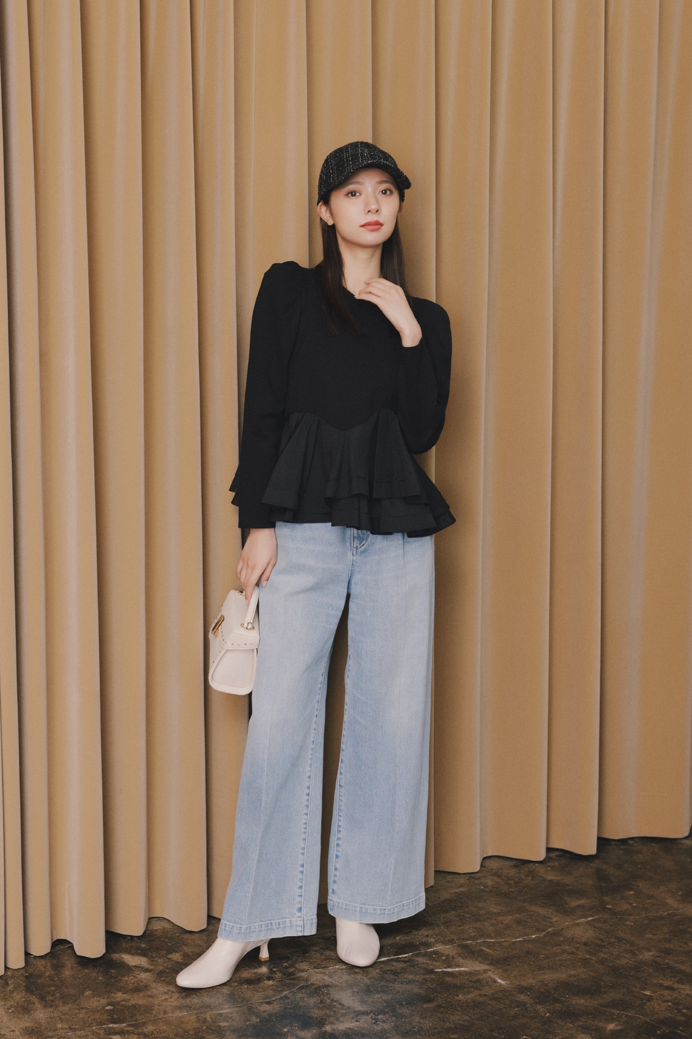 黒いトップスにジーンズを着た女性が正面を向いている画像