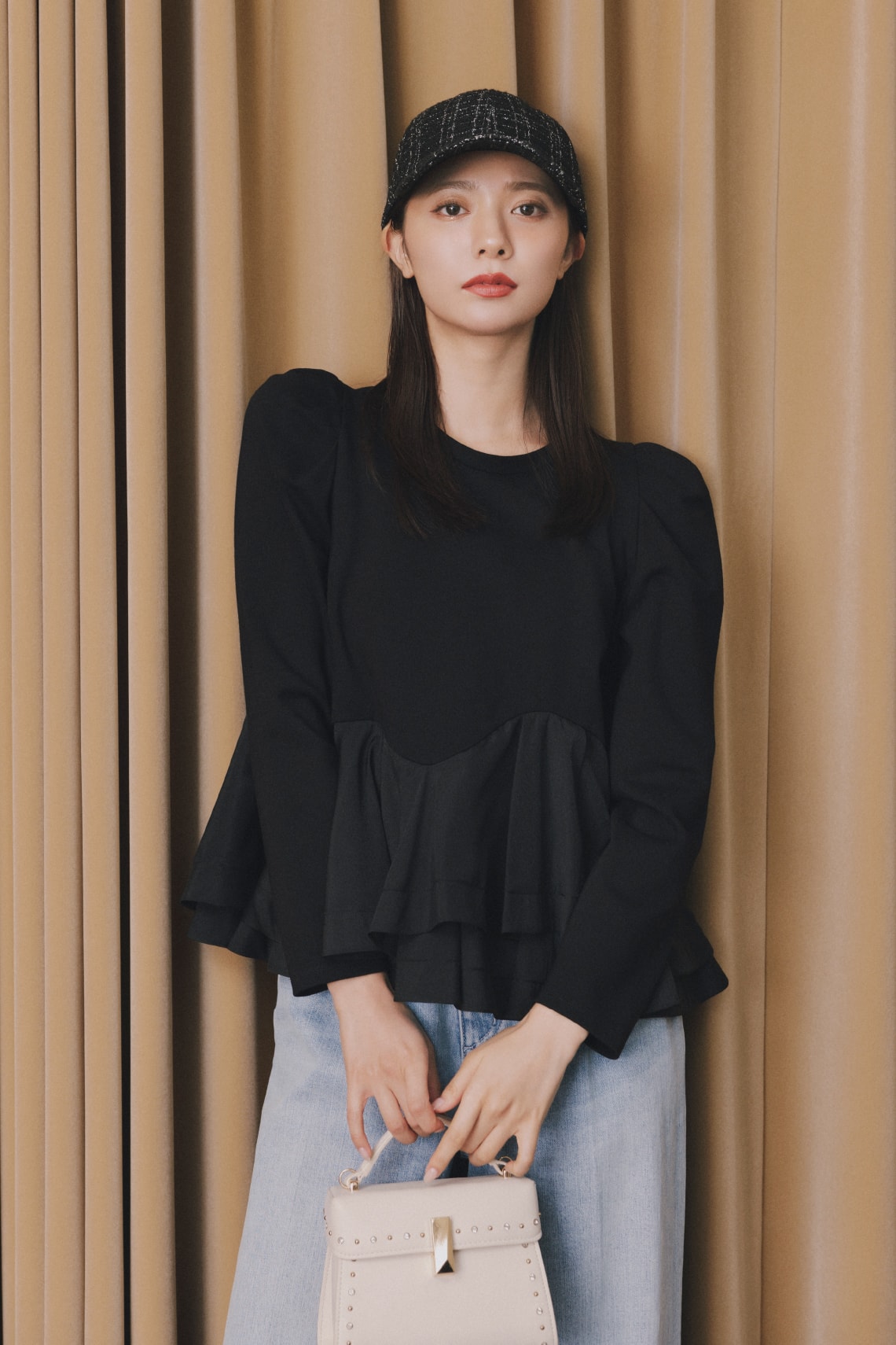 黒いトップスにジーンズを着た女性が正面を向いている画像
