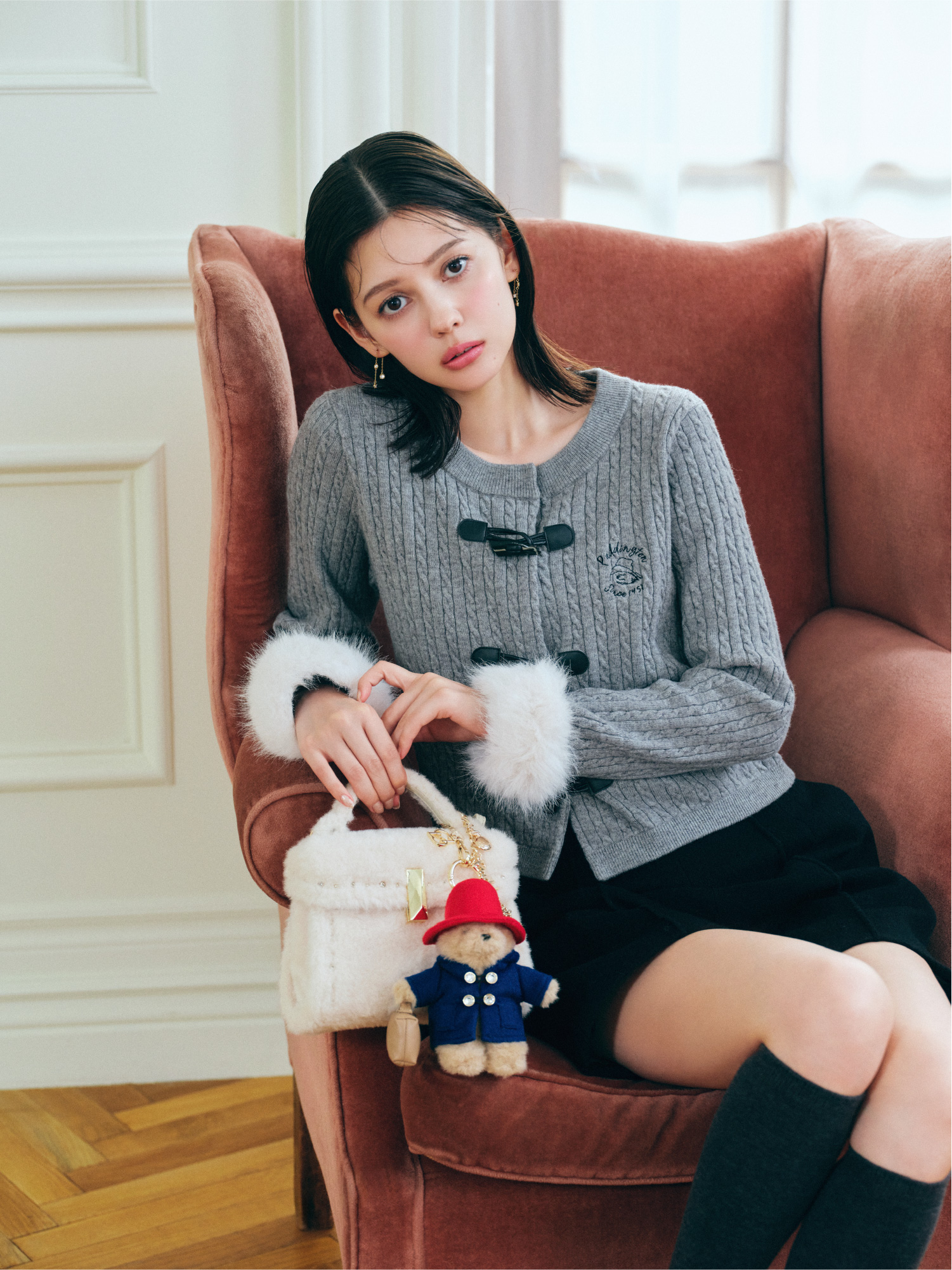 グレー色の【パディントン™×CELFORD】ケーブルカーディガン、ブラック色のバリエミニマルショートパンツ、アイボリー色の【パディントン™×CELFORD】【リュタン】ビジュースタッズボアポシェットを着用したモデル画像