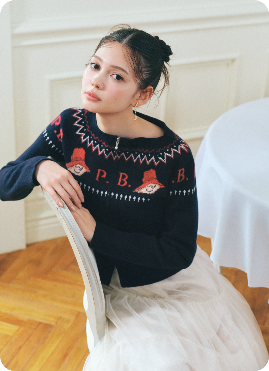 ネイビー色の【パディントン™×CELFORD】ダブルジャガードジップカーディガン、アイボリー色のチュールティアードスカートを着用したモデル画像