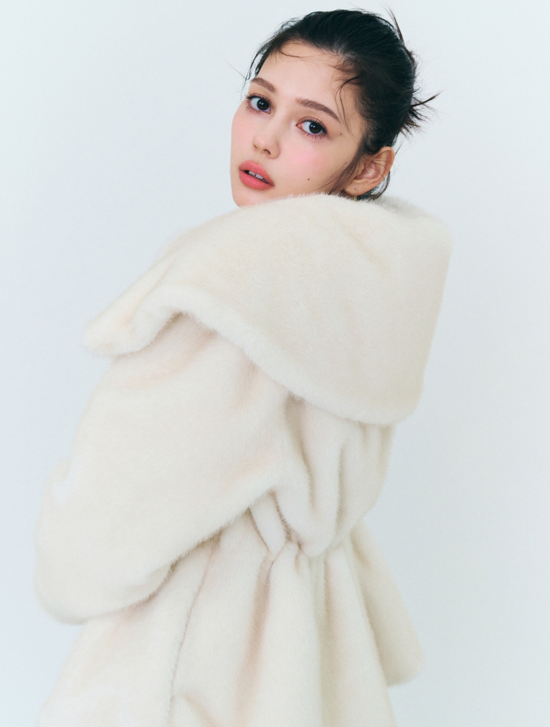 アイボリー色のビッグカラーペプラムファージャケットを着用したモデル画像