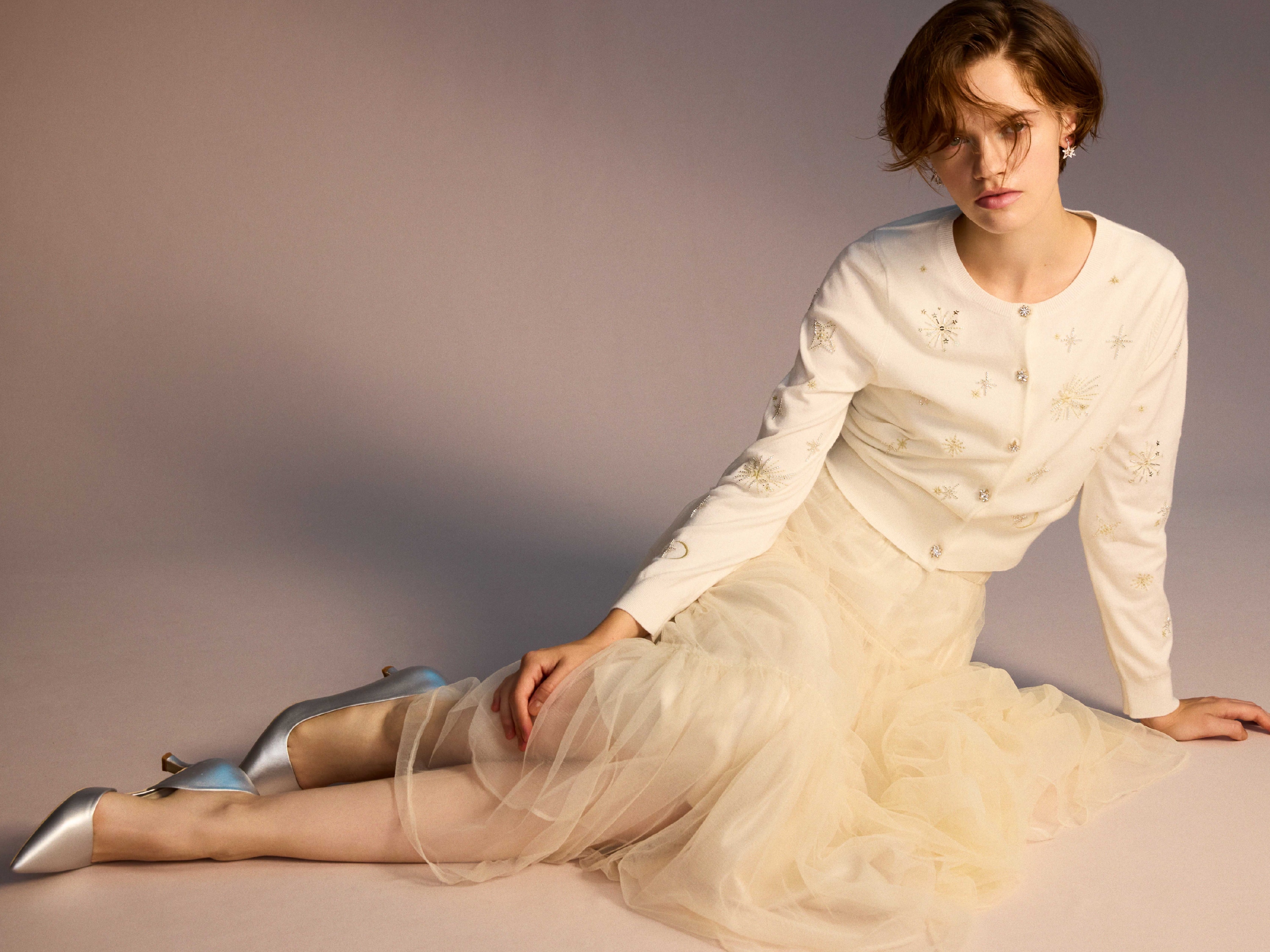 白のスターリー刺繍ニットアンサンブル・アイボリーのチュールティアードスカート・スターリービジューイヤリング・リボンクリップ付きパンプスの着用例