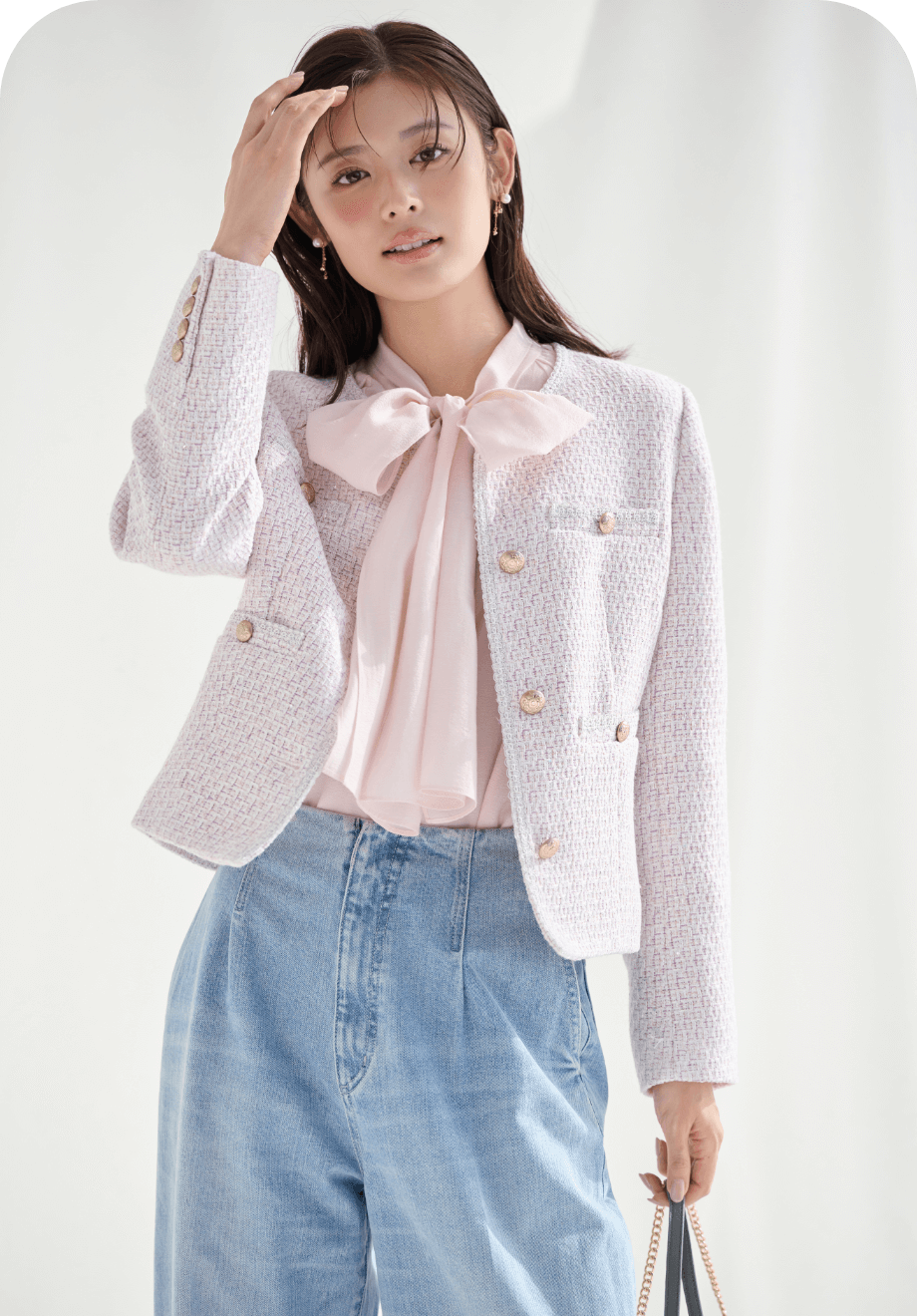 ピンク色のミドル丈ノーカラーツイードジャケットとビッグリボンセミシアーブラウスを着用したモデル画像