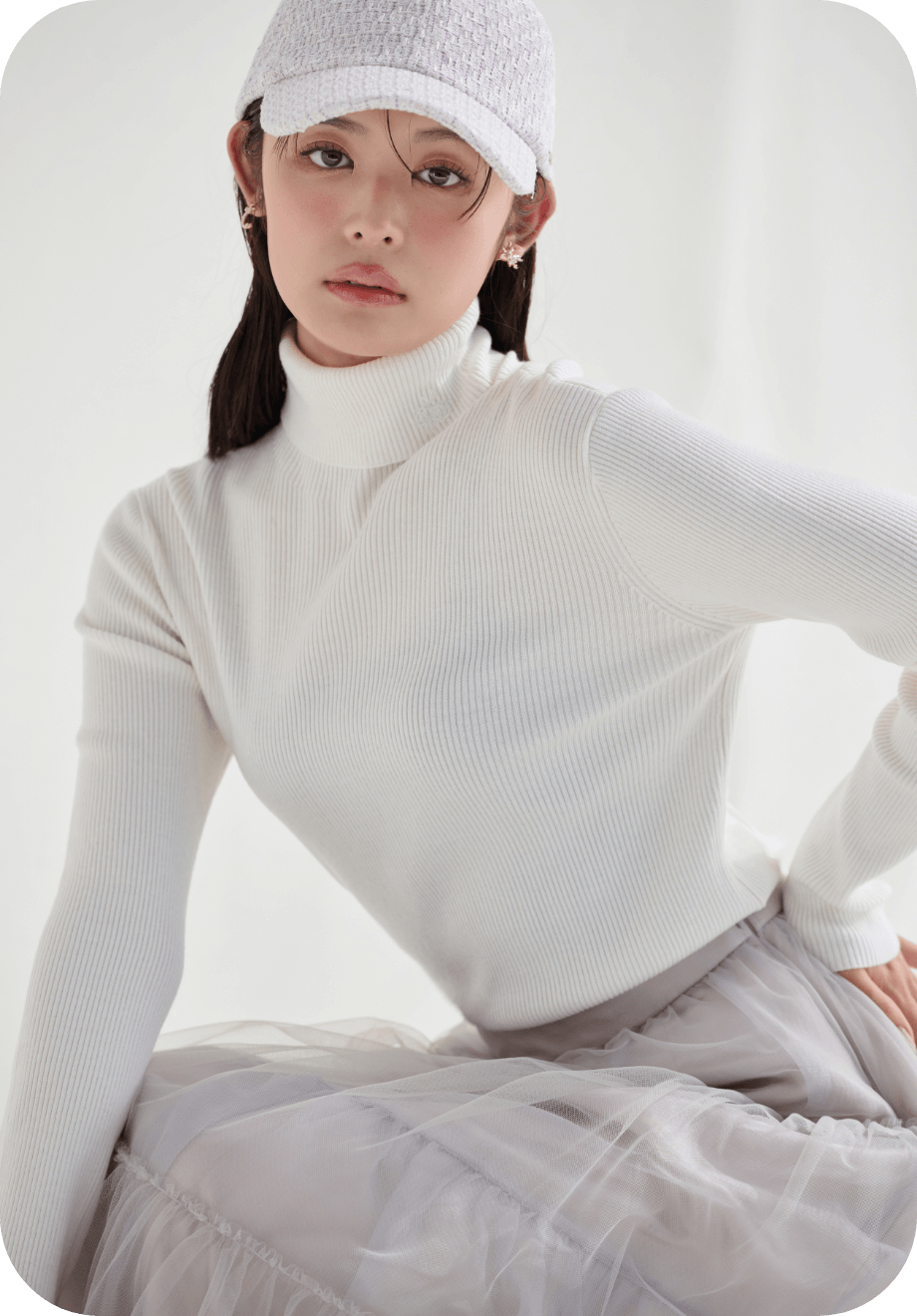 カリグラフィー刺繡シルク混リブニットプルオーバーとロゴメタル付きツイードキャップを着用した女性のイメージ