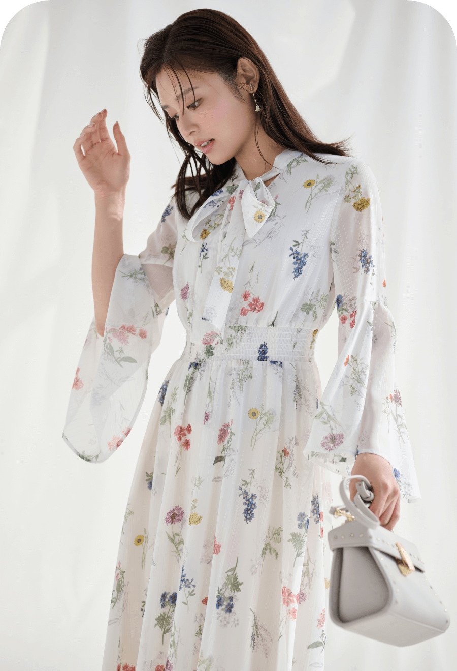 フラワープリントボウタイワンピース、【パディントン™×CELFORD】ビジューハットイヤリング、リュタンビジュースタッズポシェットを着用したモデル画像