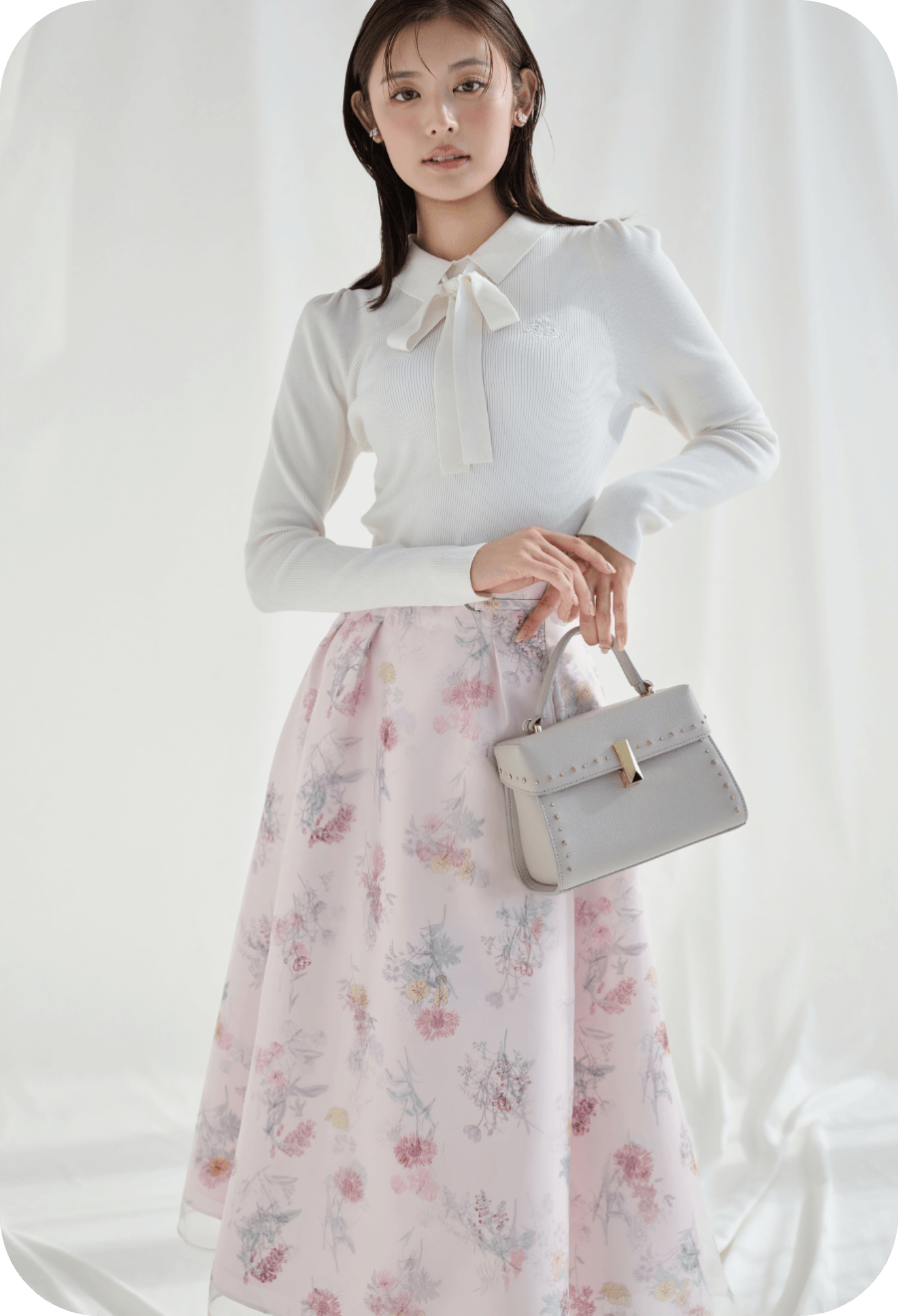 ボウタイリボン衿付きニットプルオーバー、レイヤードフラワープリントスカート、フラワービジューPetitイヤリング、リュタンビジュースタッズポシェット（Ｍ）、ロゴバックル付きバックストラップミュールの着用イメージ