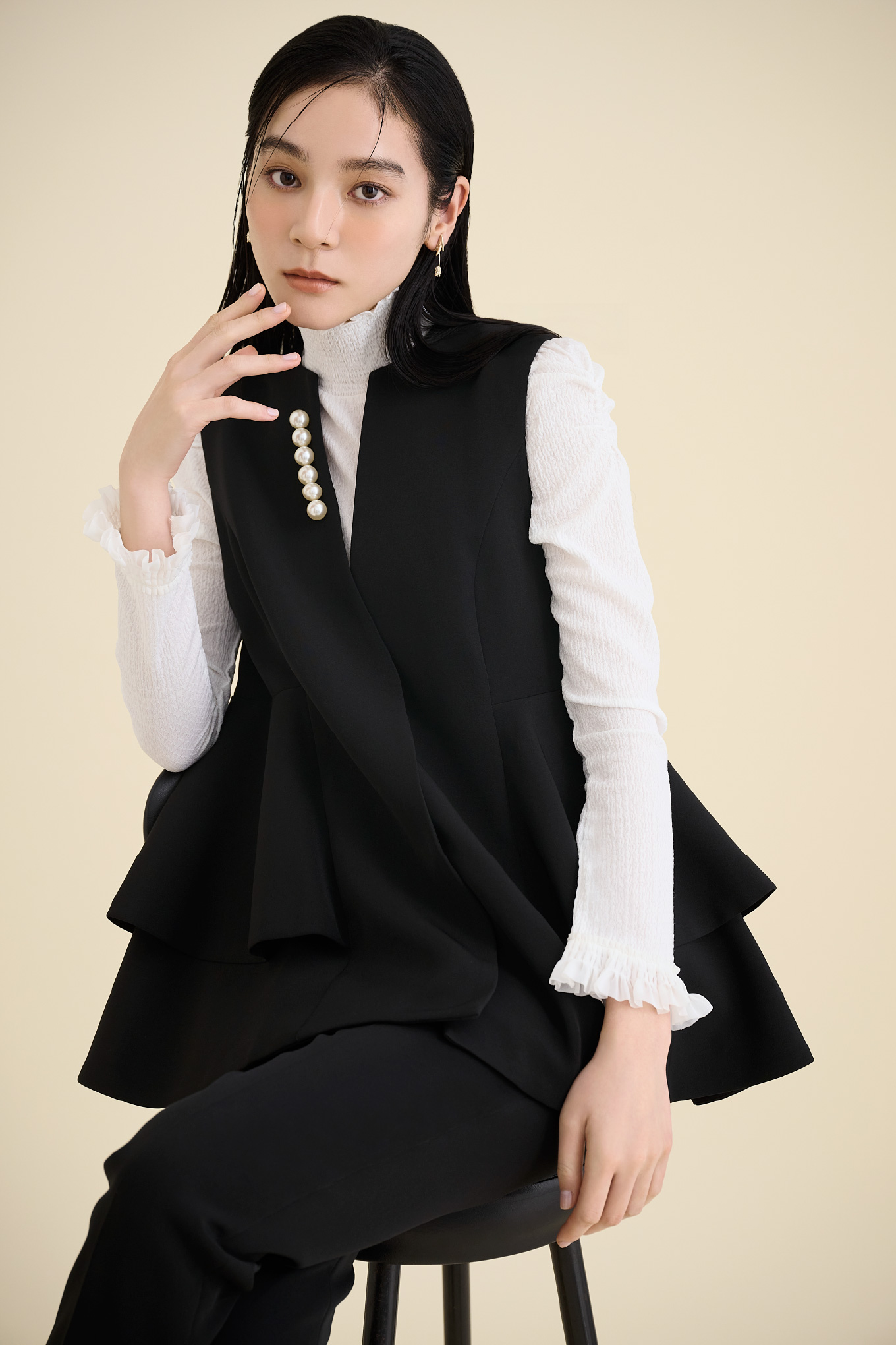 ブラック色のペプラムパールジレ、テーパードパンツと白色のシャーリングカットソートップスを着用したモデル画像