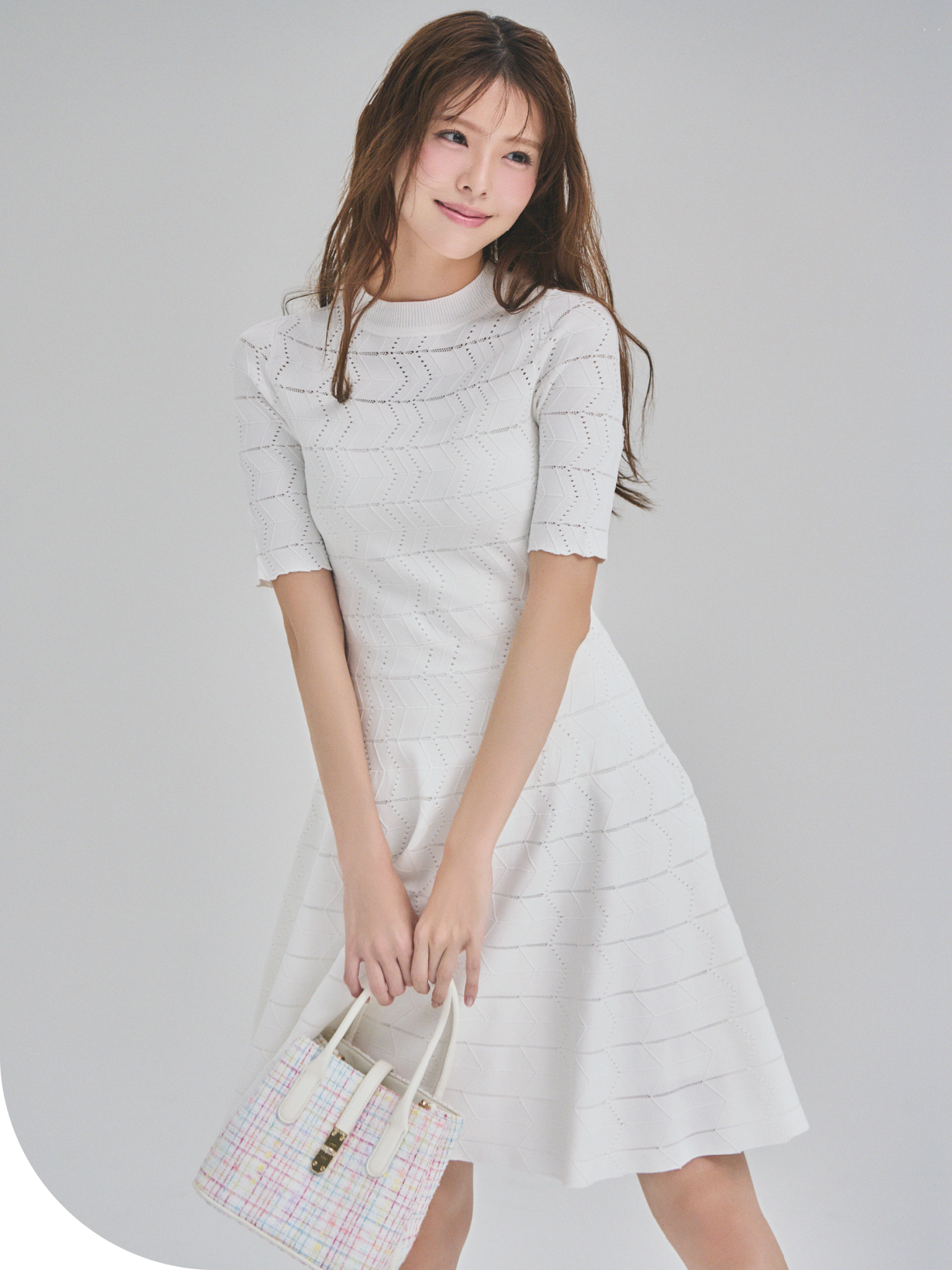 アイレット柄ミニワンピースとメタルポイントツイードトートバッグを着用した女性のイメージ