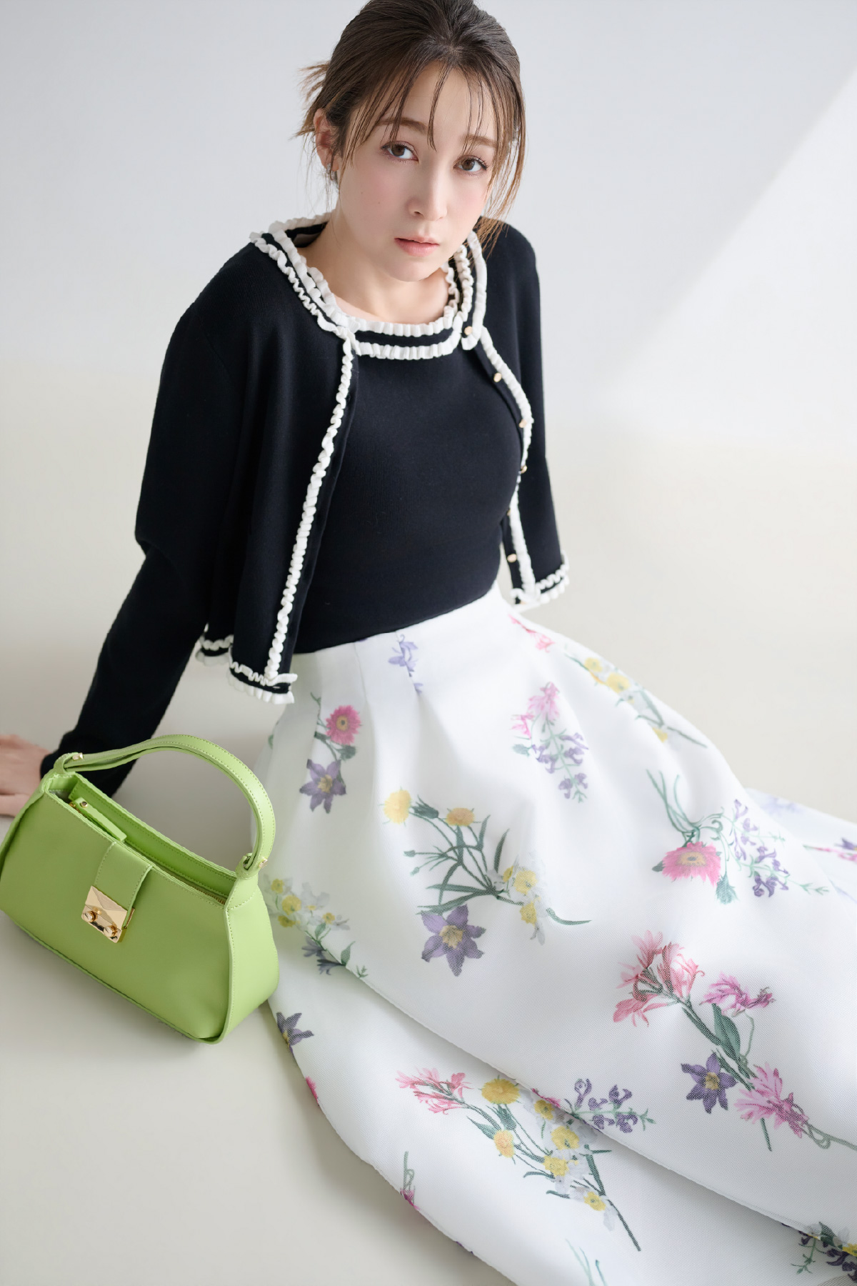 ブラック色のフリルトリムニットアンサンブル、ミニメッシュフラワースカート、ビジューチューリップピアス、2WAYワンハンドルショルダーバッグを着用したモデル画像