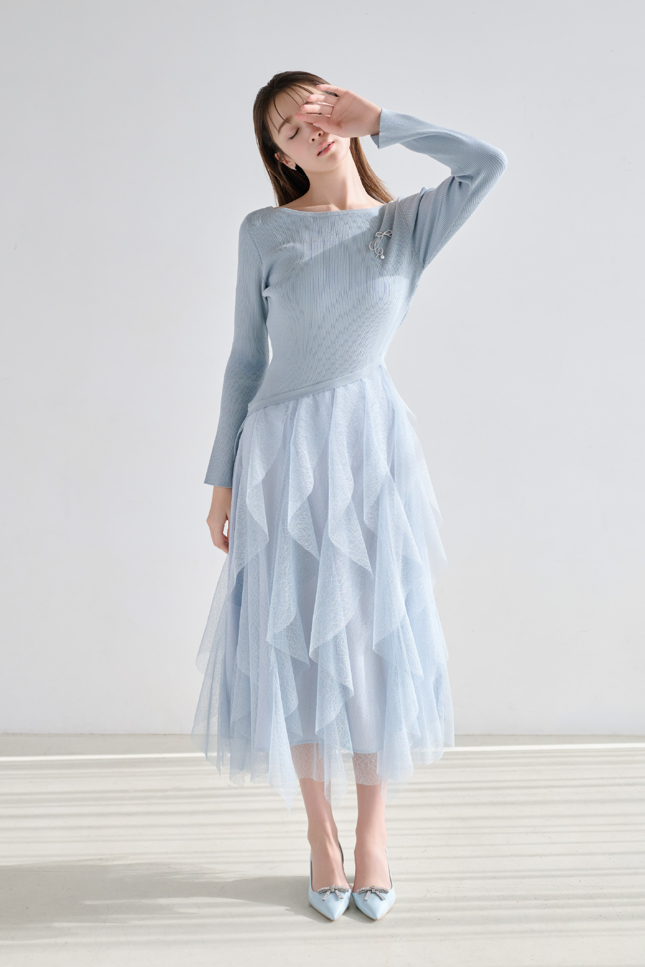 空色のラッフルスカートドッキングニットワンピ、ビジューチューリップピアス、シンプリービジューリボンブローチ、Cロゴパール付きビジューブローチを着用したモデル画像