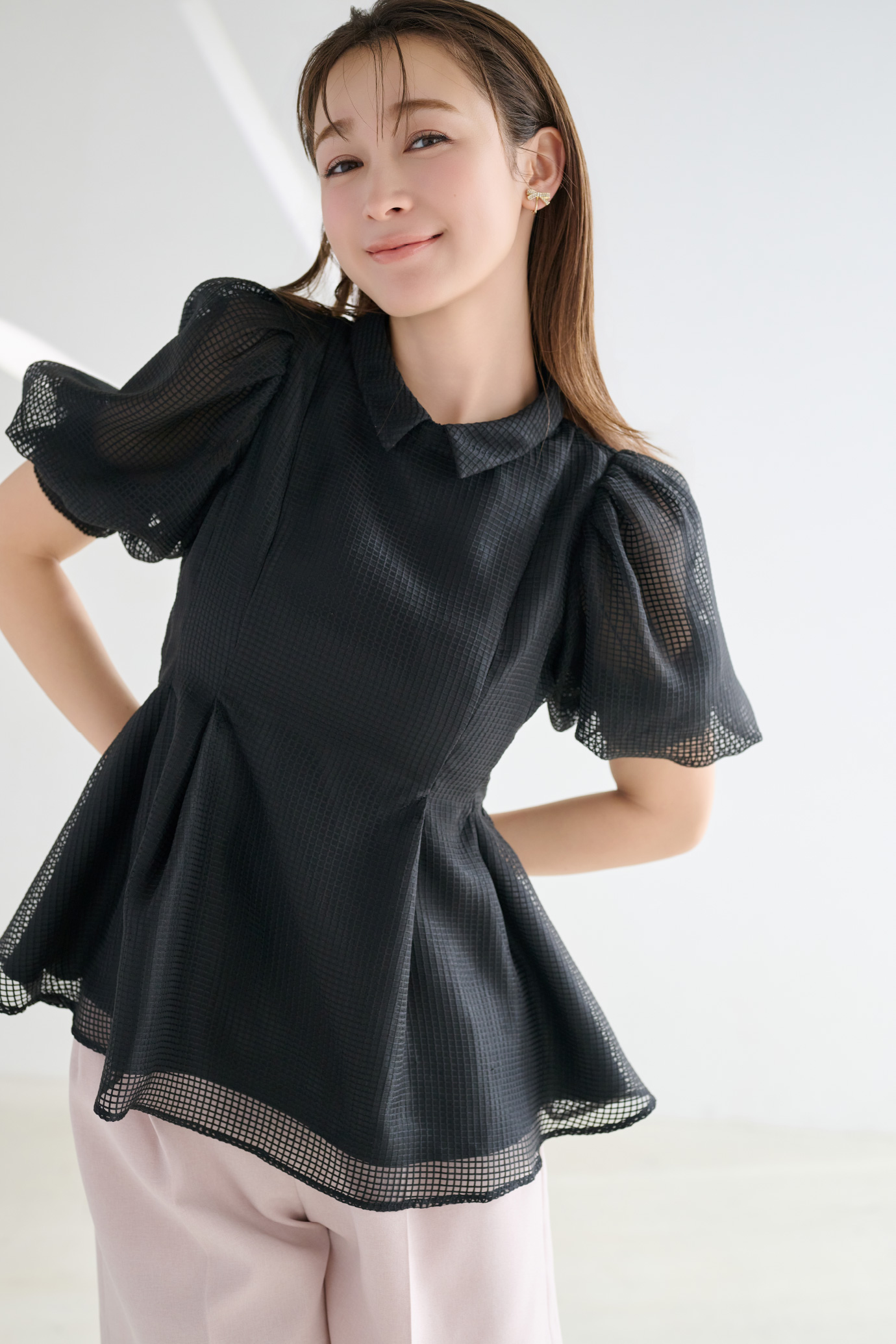 黒色の襟付きメッシュブラウス、ピンク色のベルト付きショートパンツを着用した女性のイメージ