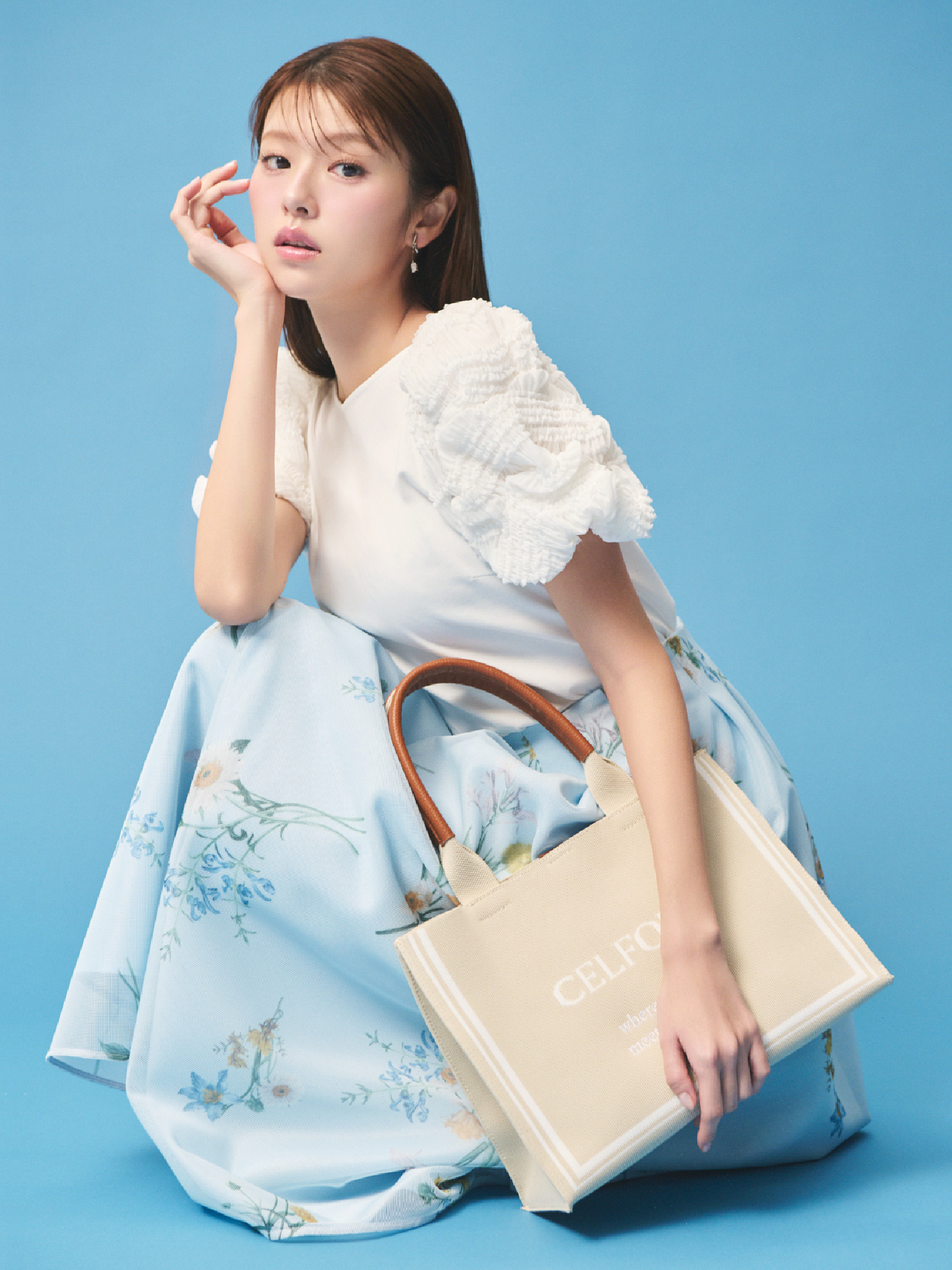 タックバルーンスリーブカットソー、ミニメッシュフラワースカート、ビジューチューリップイヤリング、CELFORDロゴニットバッグを着用して座ってるモデル画像