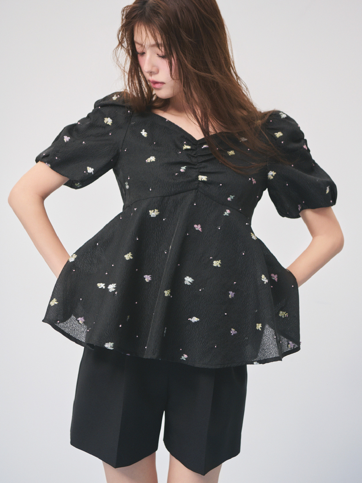 ブラック色の小花ジャガードペプラムブラウスとベルト付きショートパンツを着用したモデル画像