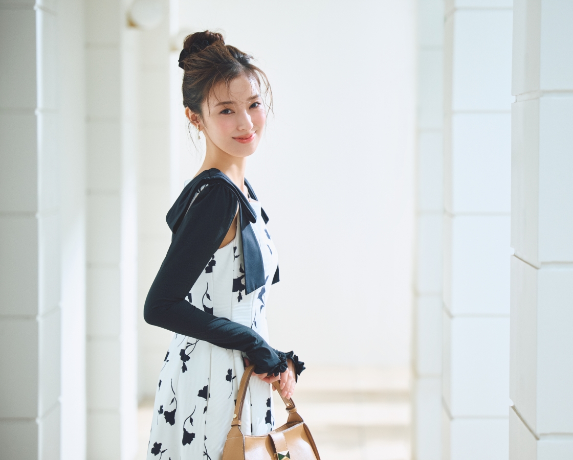 ラッシュガードショルダーリボンワンピース、ビジューチューリップイヤリング、アームカバーを着用した女性