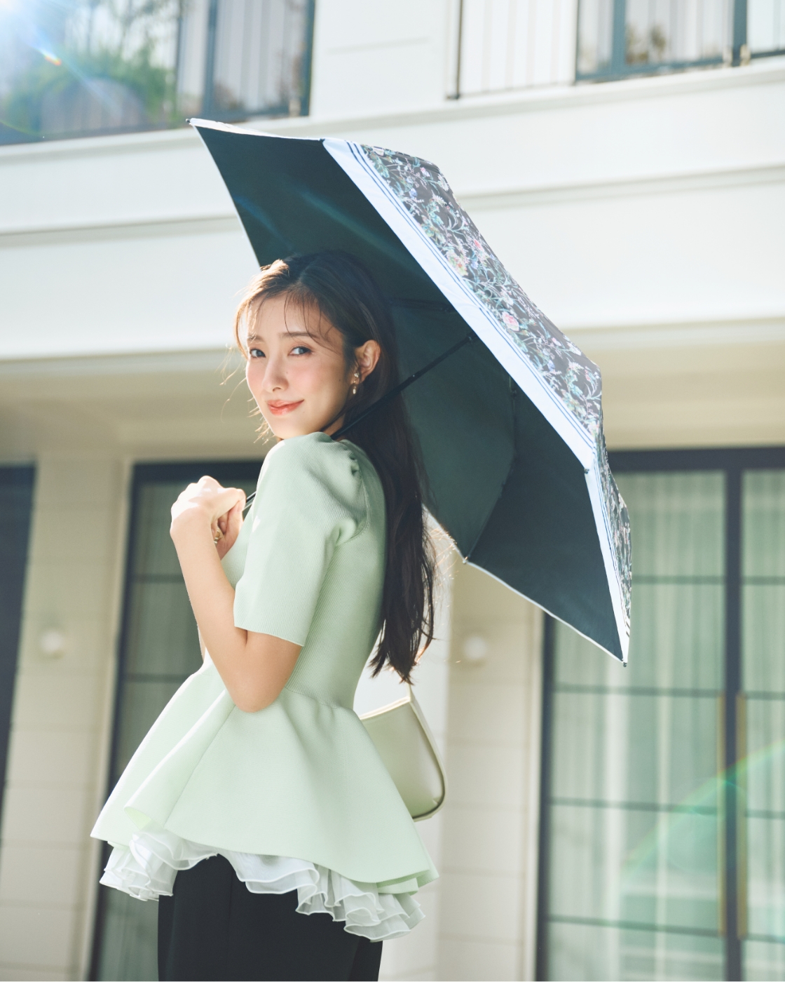 ペプラムニットドッキングプルオーバー、フラワープリントコラボレーション日傘、ハートパヴェビジューイヤリングを着用した女性