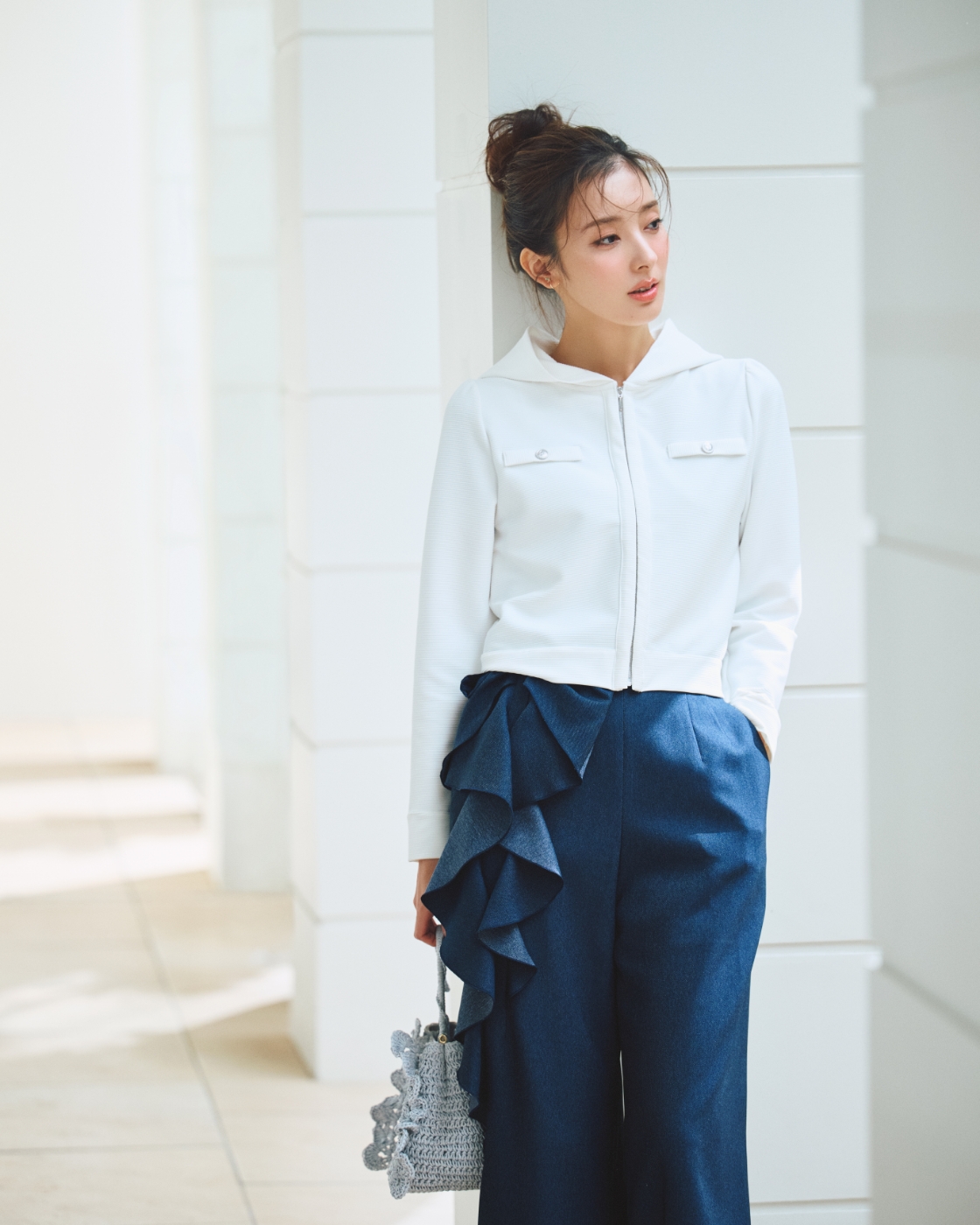 ポケットカーディガン、リボンワイドパンツ、ビジューチェリーイヤリング、かぎ編みペーパーフリルバッグを着用した女性