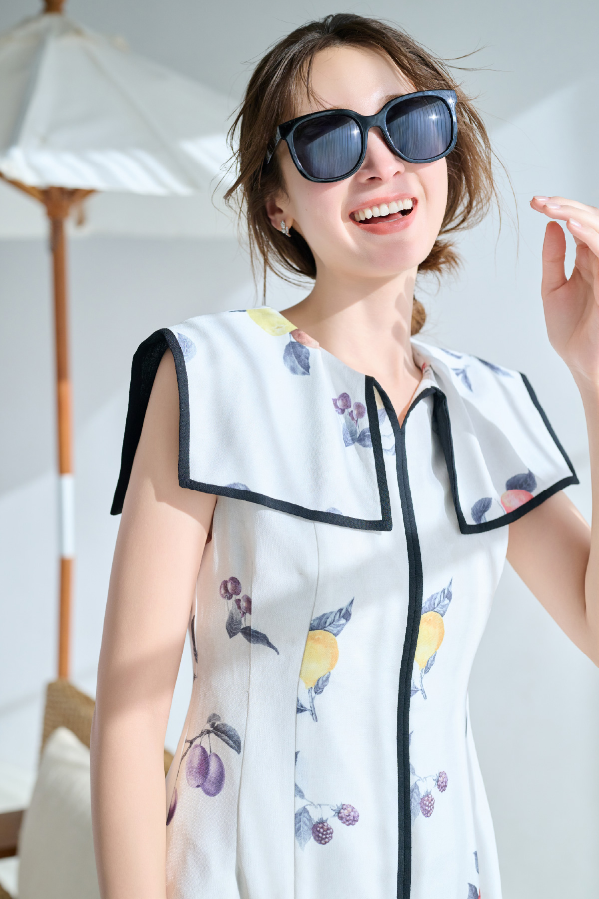 ブラック色の偏光レンズサングラスとフルーツプリントワンピースを着用したモデル画像